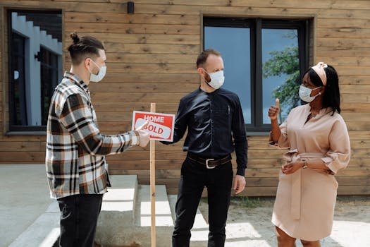People discussing a home sale while wearing masks for safety during COVID-19.